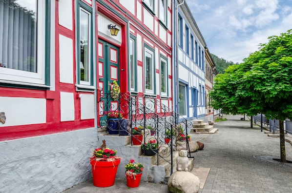 A traditional European building with a red and white facade, a staircase leading to the entrance, and potted plants on the ground. - Apartment 'Haus Behrendt' with Mountain View, Balcony and Wi-Fi (Walkenried)