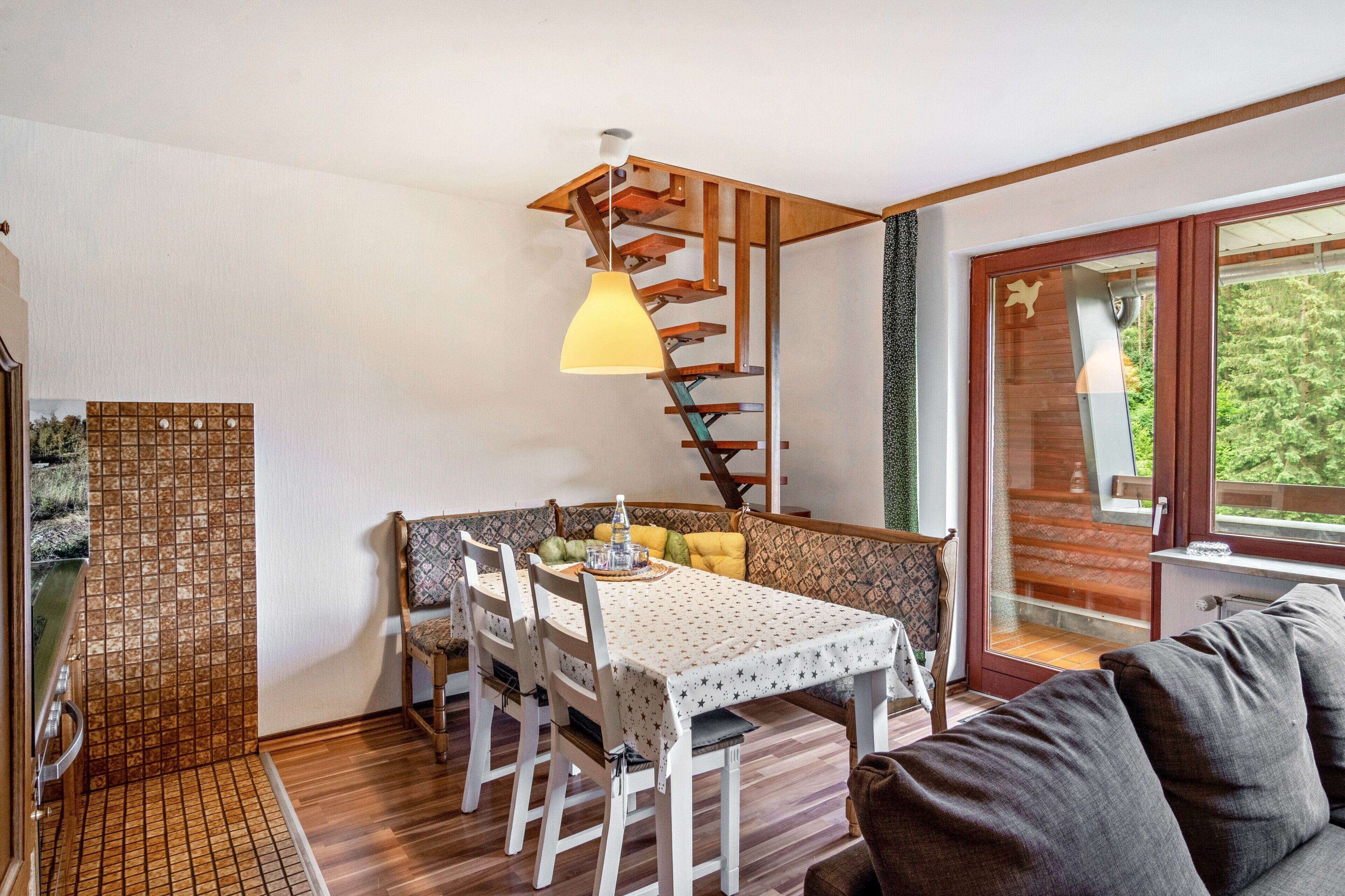 Un coin repas avec un escalier en bois, une table avec des chaises et un canapé.