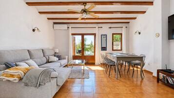A living room with a sofa, a coffee table, and a dining area with chairs and a table.