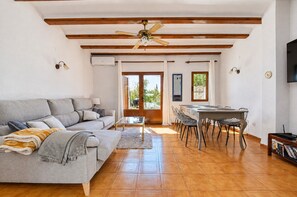 A living room with a sofa, a coffee table, and a dining area with chairs and a table.