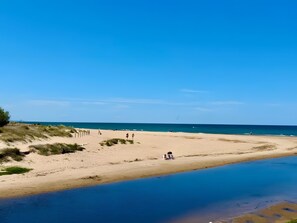 A beach with a clear sky, a calm sea, and a sandy shore.
