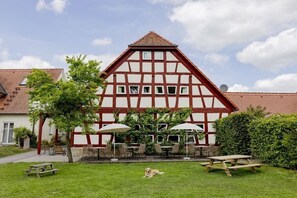 Ein traditionelles Fachwerkhäuschen mit geneigtem Dach, Außenbereich und einem Picknicktisch.
