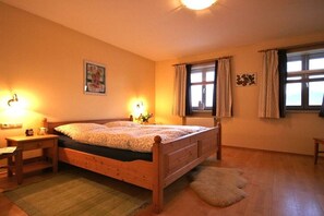 Ein Schlafzimmer mit einem hölzernen Bett, Nachttischlampen, einem Fenster mit Vorhängen und einer Heizung.