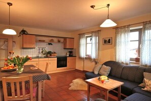 Ein kompakter Wohnbereich mit Küchenzeile, Essbereich und einer Couch.