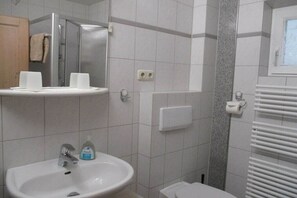 Une salle de bain équipée d’un lavabo, d’un miroir, d’un porte-serviettes et d’un espace douche.