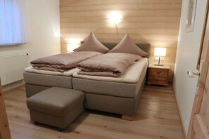 Une chambre à coucher avec un lit, deux tables de chevet, une commode et un plancher en bois.