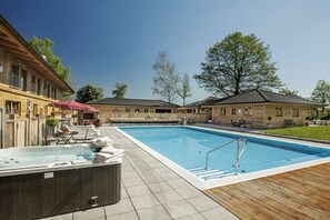Ein Schwimmbecken mit Whirlpool, LiegestĂŒhlen und einer Holzterrasse.