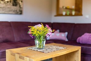 Ein Holztisch mit einer Glasvase, in der Blumen stecken, auf einer Tischdecke.