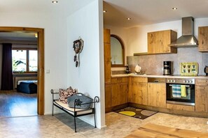 Eine moderne Küche mit Holzausstattung, integriertem Backofen und einer Essecke mit einer Bank sowie dekorativen Wandbildern.