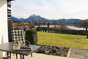 Ein Balkon mit Blick auf einen See, Berge und einen Garten.