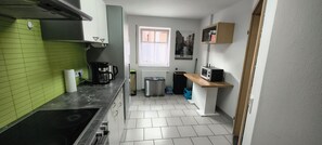 Una cocina compacta con estufa a gas, cafetera y microondas.