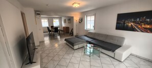A modern living room with a sofa, a glass coffee table, and a flat-screen TV.