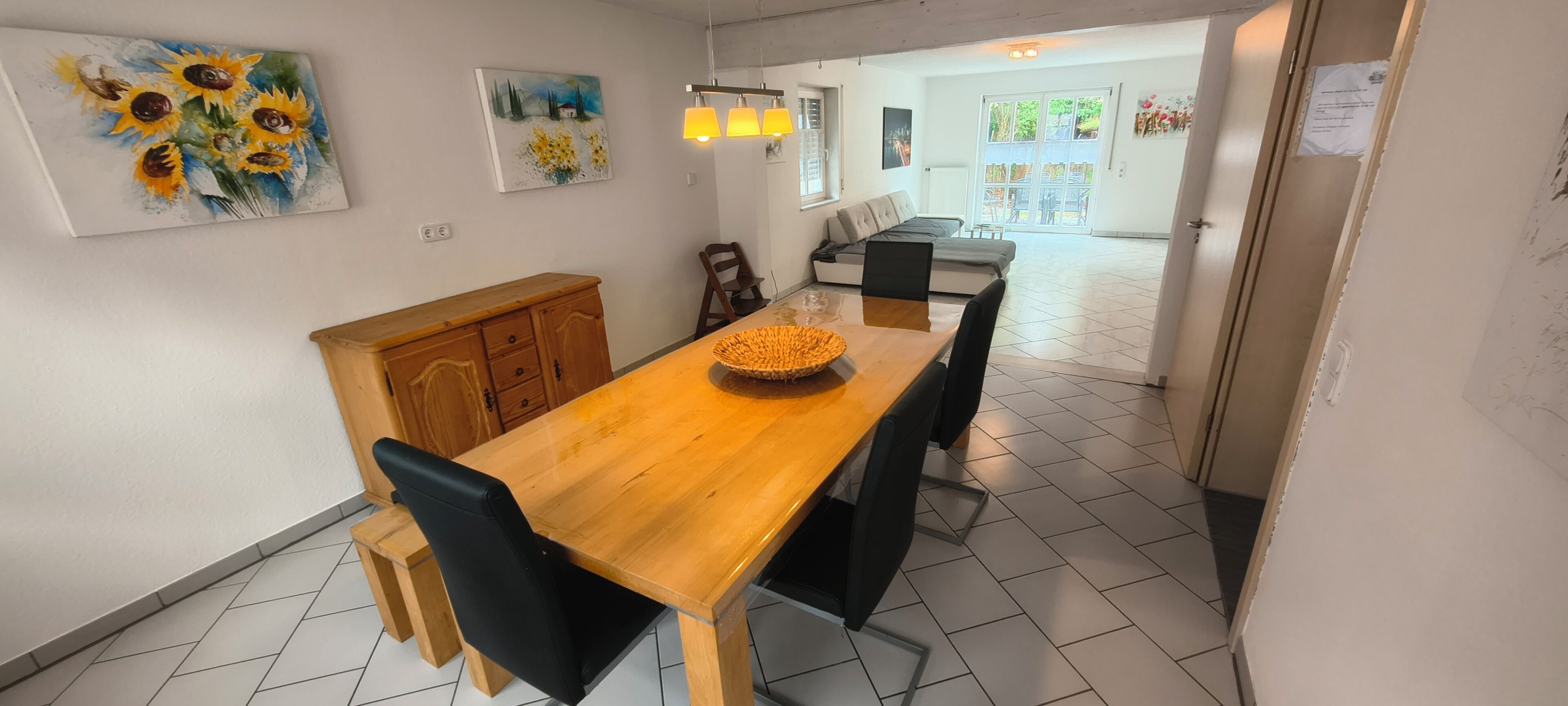 Ein Essbereich mit Holztisch, Stühlen und einer gewebten Schale als Mittelpunkt.