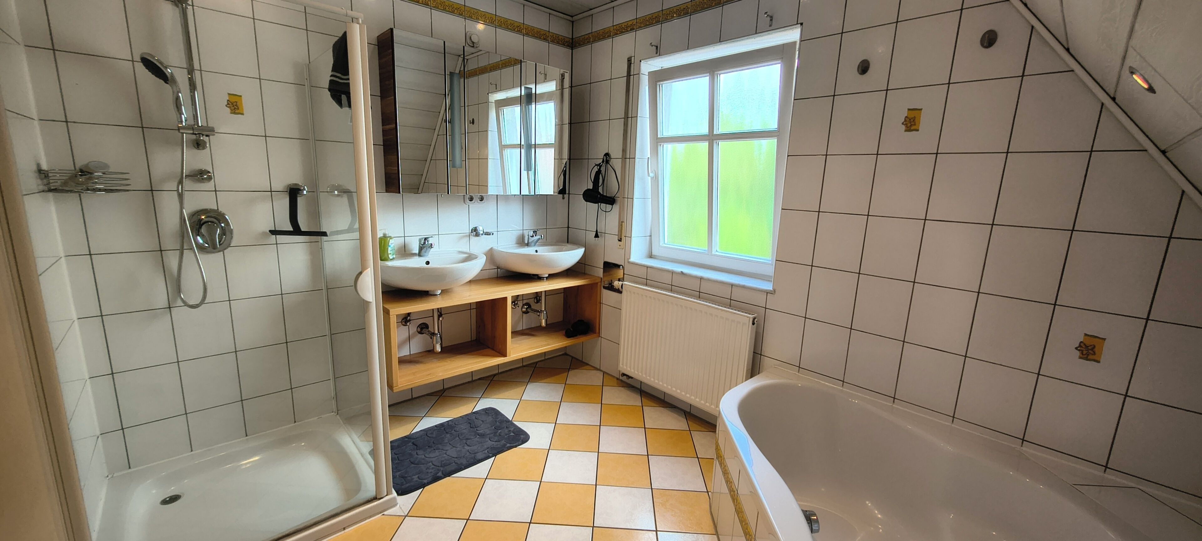 Une salle de bain avec une baignoire, deux lavabos, une douche et une fenêtre.