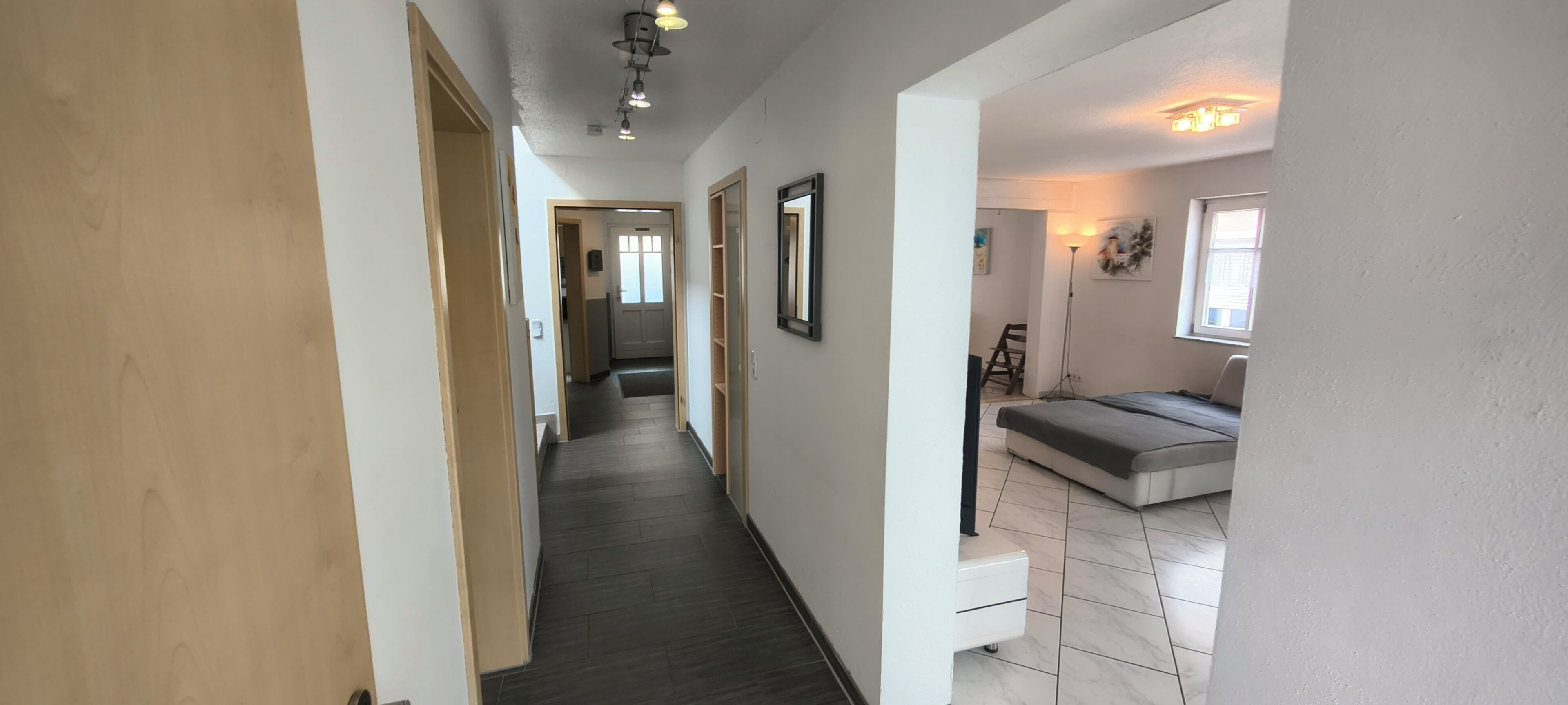 A hallway with a bed, a desk, and a chair.