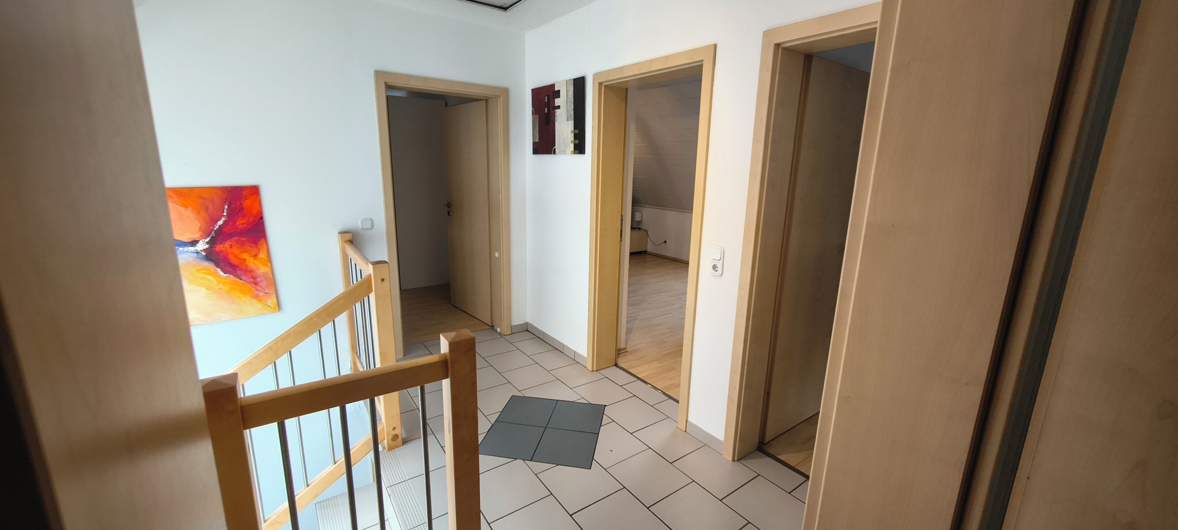 A hallway with wooden doors, a staircase, and a tiled floor.
