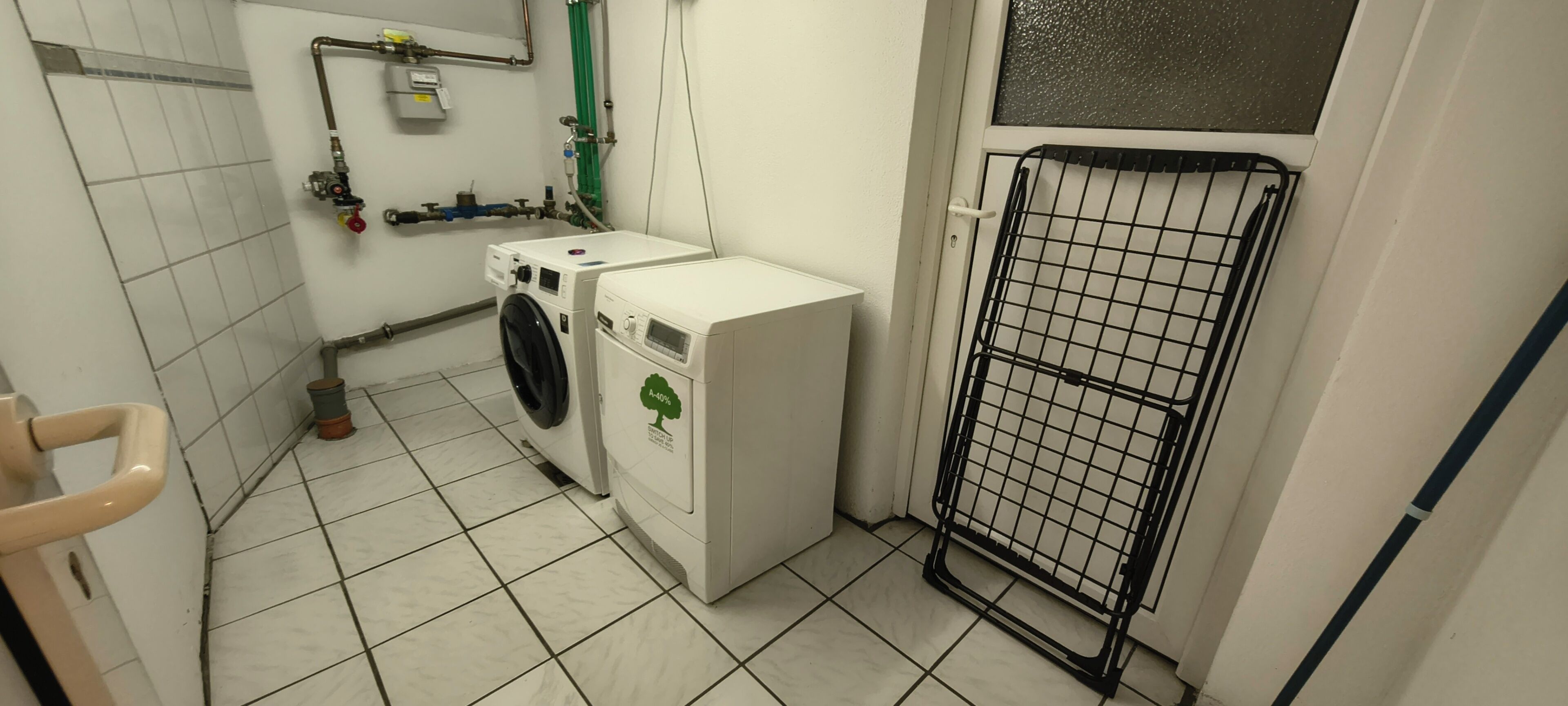 Ein Waschraum mit Waschmaschine, Trockner und einem Metallgitter.