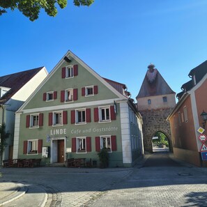 Ein Gebäude mit einem Schild, auf dem 'Linde Café und Gasthöfe' steht, vor einer gepflasterten Straße.