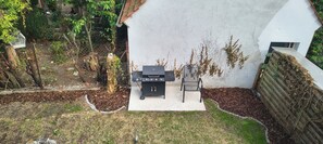 A backyard with a barbecue grill, a chair, and a small table.