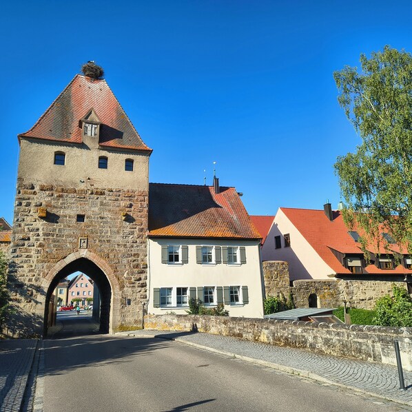 Ein historischer SteinTurm mit rotem Ziegeldach, eine Kopfsteinpflasterstraße und traditionelle Gebäude mit Satteldächern.