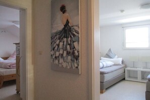 Un dormitorio con cama, mesita de noche, lámpara y una obra de arte colgada en la pared.