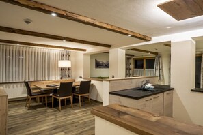 Una cocina moderna con encimera de madera, un lavamanos y una zona de comedor con sillas y una mesa.