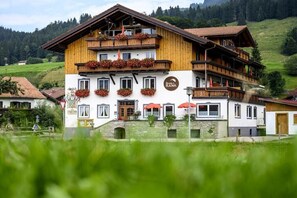 Un hotel de varios pisos con balcones, macetas de flores y un letrero que dice 'Hotel Rank'.