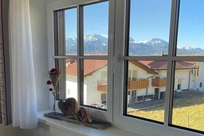 Ein Fenster mit Blick auf ein Gebirge und ein Gebäude mit rotem Dach.
