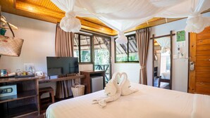 Una camera d'albergo con un letto, una scrivania con televisore, un computer e un cesto in vimini.