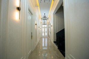 A hallway with a chandelier, a television, and a door at the end. - FERIDE'S boutique hotel  (Samarqand)
