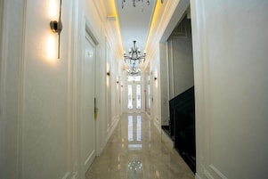 A hallway with a chandelier, a television, and a door at the end.