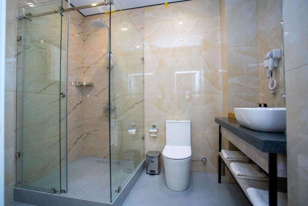Une salle de bain moderne avec une douche à parois de verre, des toilettes blanches et un lavabo doté d’un plan de travail en marbre.