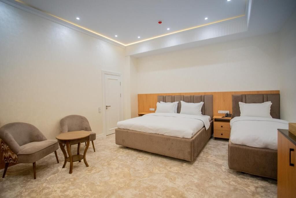 Un dormitorio con una cama, dos mesitas de noche, una silla y una pequeña mesa.