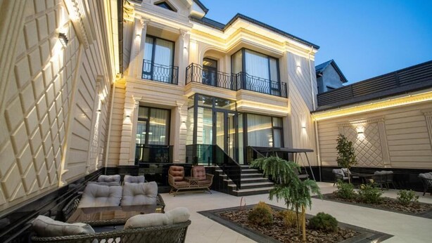 A two-story building with a balcony, outdoor seating area, and a staircase leading to the entrance.
