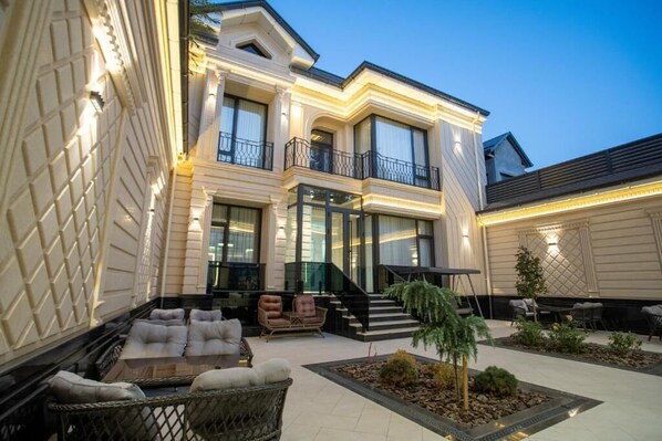 A two-story building with a balcony, outdoor seating area, and a staircase leading to the entrance.