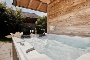 Ein Whirlpool mit einer Holzverkleidung und einem Holzbau im Hintergrund.