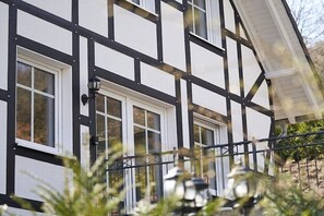 Un edificio con fachada blanca y entramado de madera negra, con varias ventanas y un balcón visible.
