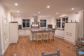 Una cocina moderna con una isla central, taburetes de madera y armarios blancos.