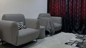 Olohuoneessa on kaksi erilaista, houndstooth-kuvioitua sohvaa, harmaa matto ja mustavalkoinen kuvioitu matto.