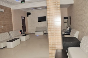 Um lobby moderno com área de estar, televisão e ar condicionado de parede.