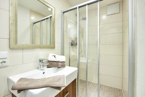 Un baño con lavamanos, espejo y cabina de ducha de vidrio.