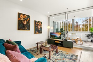 A modern living room with a sofa, coffee table, TV, and artwork on the wall. - Poolside Studio Retreat Near Oxford Street (Sydney)