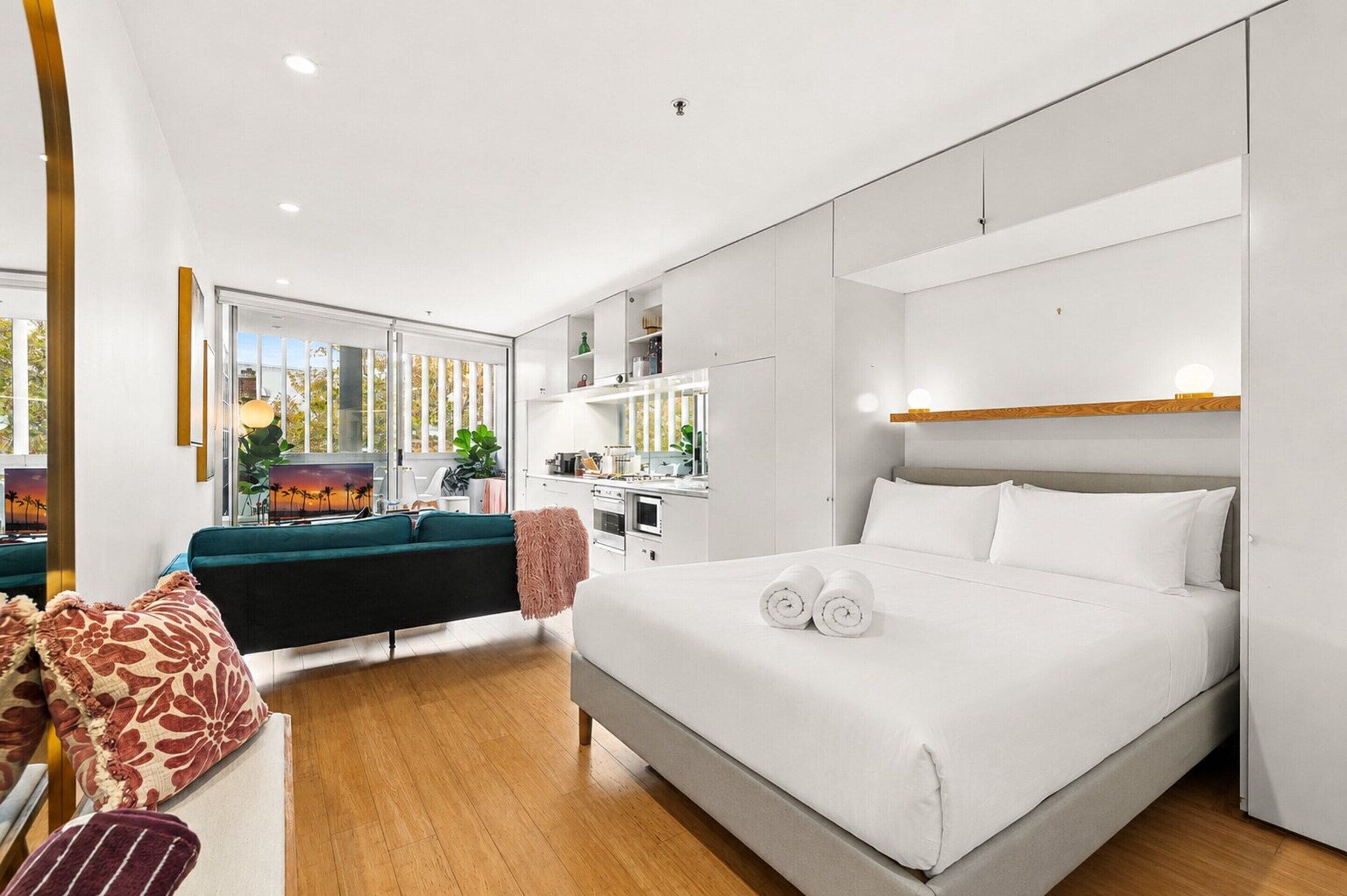 Een moderne hotelkamer met een groot bed, een zithoek met een bank, een eethoek en een keuken.