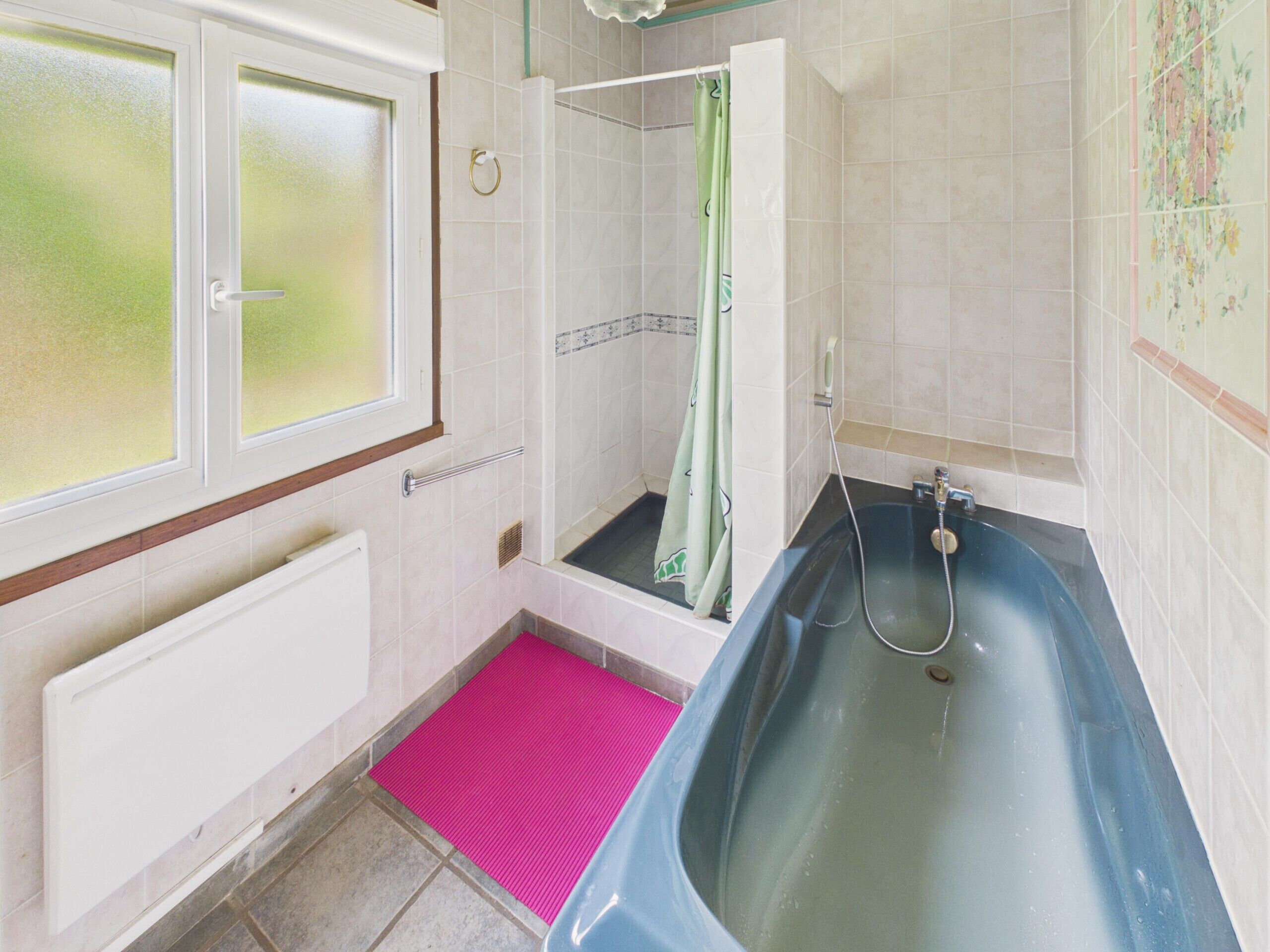 A bathroom with a bathtub, a shower, and a window.