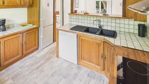 A kitchen with wooden cabinets, a refrigerator, a dishwasher, and a sink. - House for 4, enclosed garden – Périgord Noir (Saint-Cyprien)