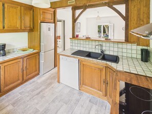 Eine Küche mit Holzausstattung, einem Kühlschrank, einem Geschirrspüler und einem Waschbecken.