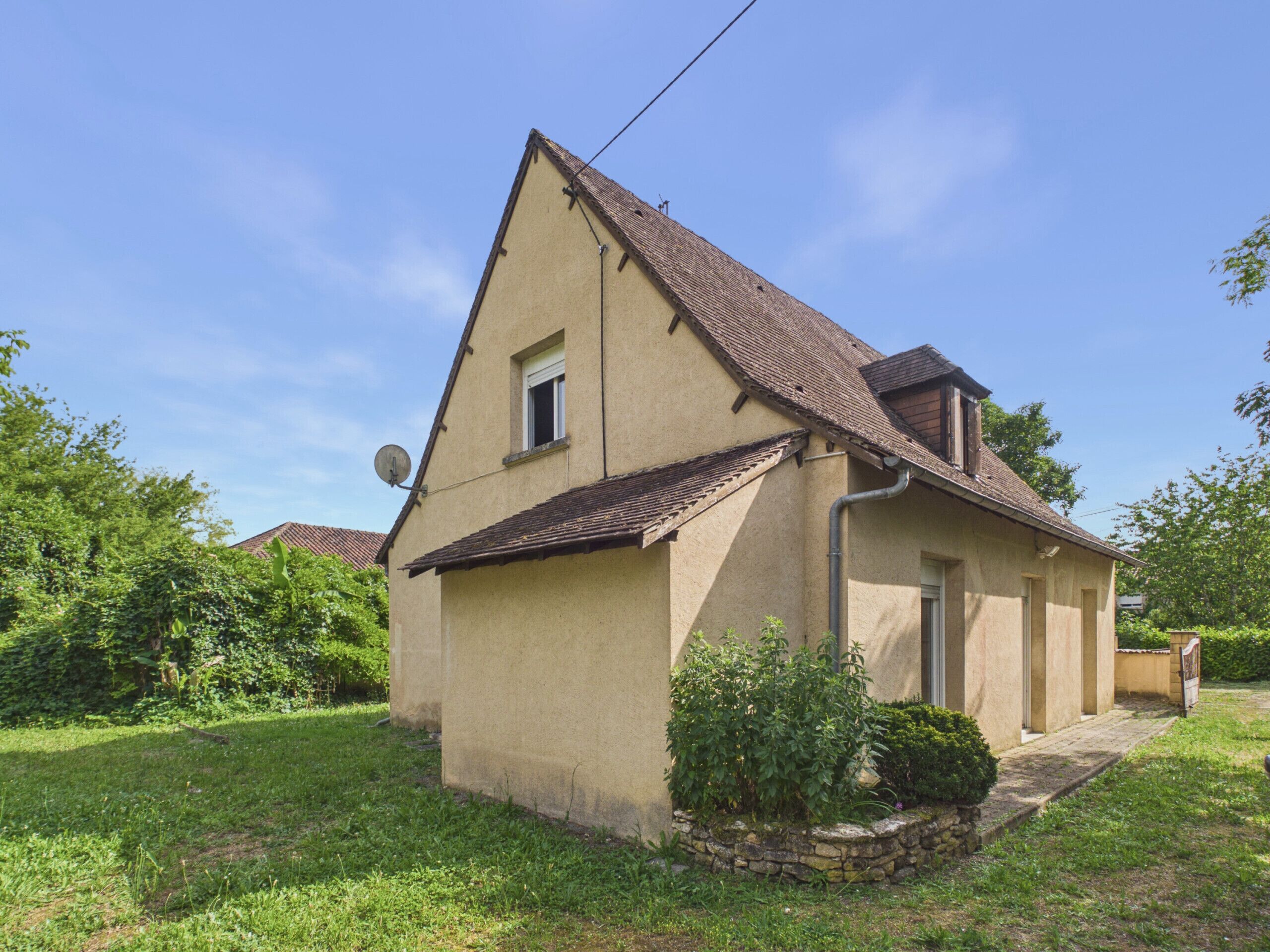Einbungalow mit geneigtem Dach, einer Satellitenschüssel und einem kleinen Garten.
