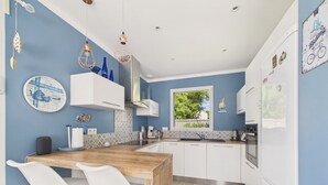A modern kitchen with white cabinets, a wooden island, and a window overlooking greenery. - House with garden, 7 adults 1 child (Saint-Michel-Chef-Chef)