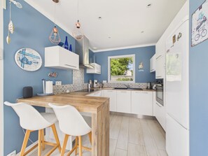A modern kitchen with white cabinets, a wooden island, and a window overlooking greenery. - House with garden, 7 adults 1 child (Saint-Michel-Chef-Chef)