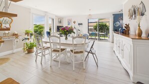 A spacious dining area with white furniture, a large window, and a view of the outdoors. - House with garden, 7 adults 1 child (Saint-Michel-Chef-Chef)